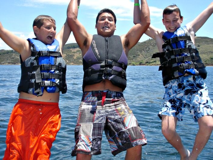 Two campers and their counselor jumping into the ocean at summer camp in Hawaii
